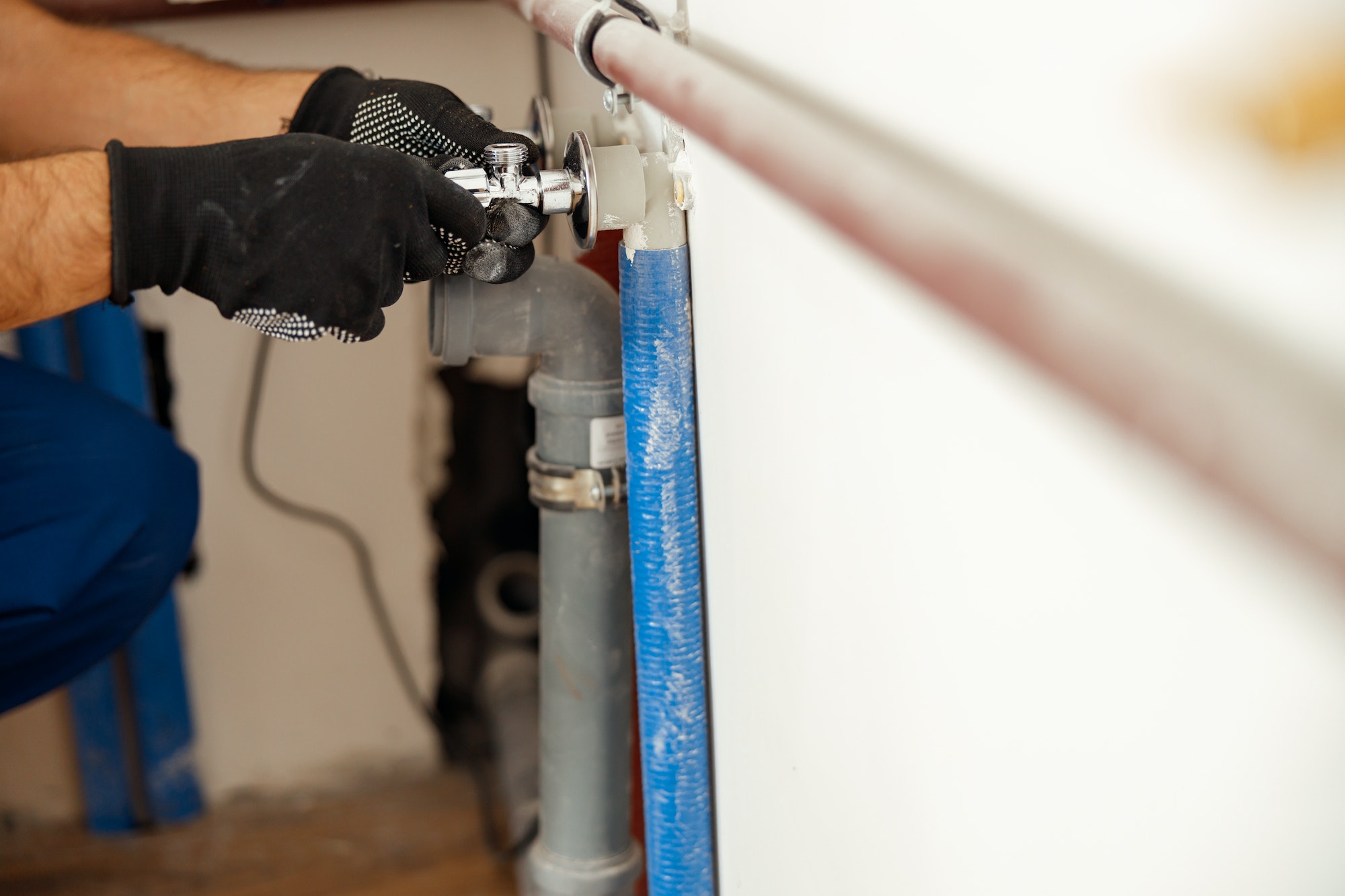 Closeup of hands of plumber checking pipes while installing heating system in apartment